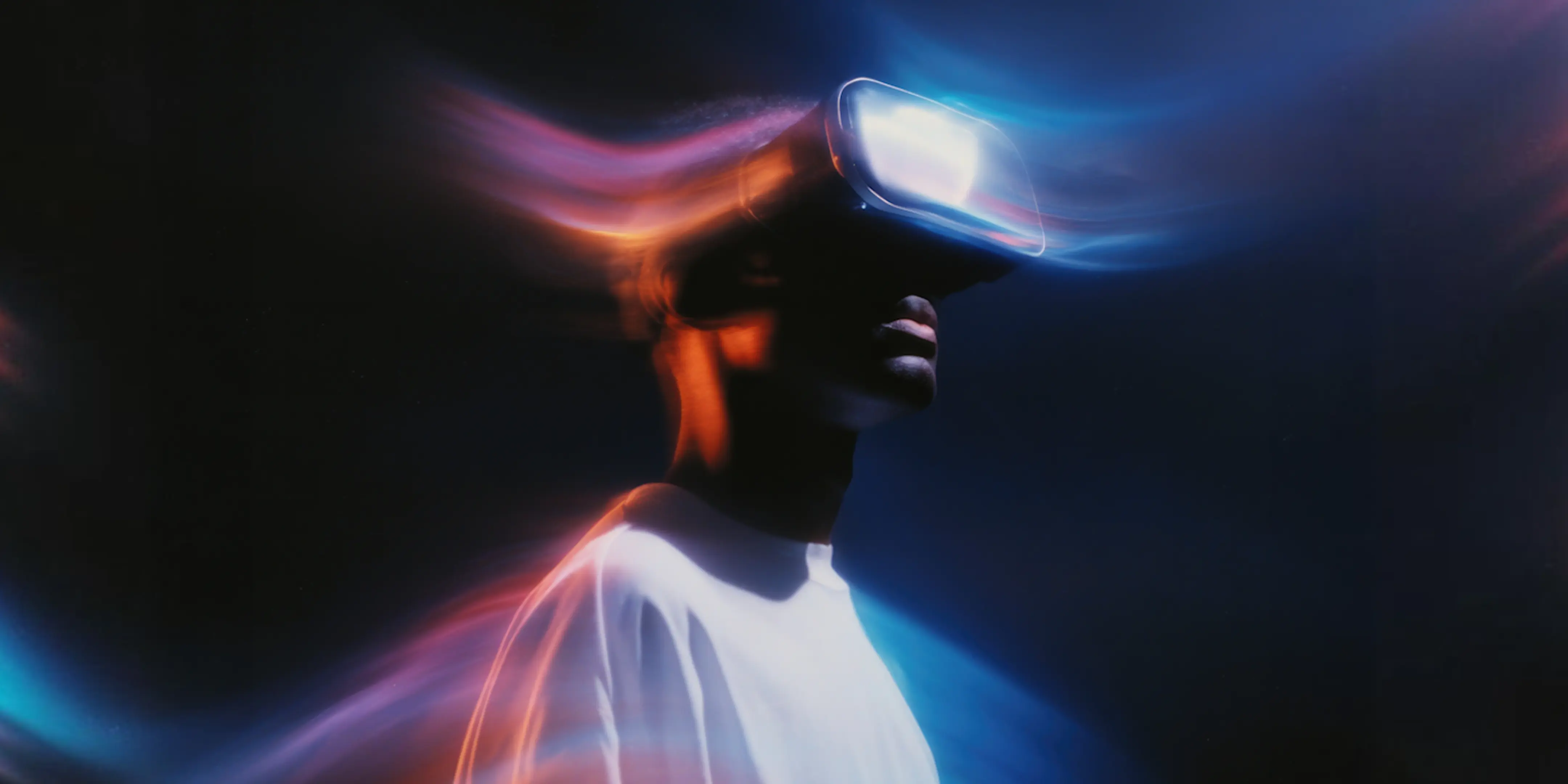 Person wearing VR headset with colorful light trails against a dark background.